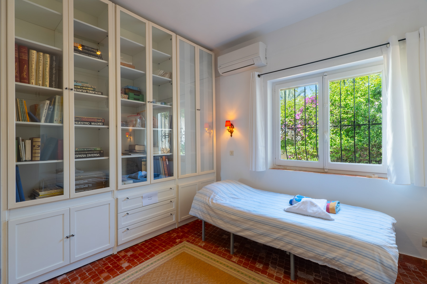 Dormitorio luminoso con estantería empotrada y vistas al jardín.