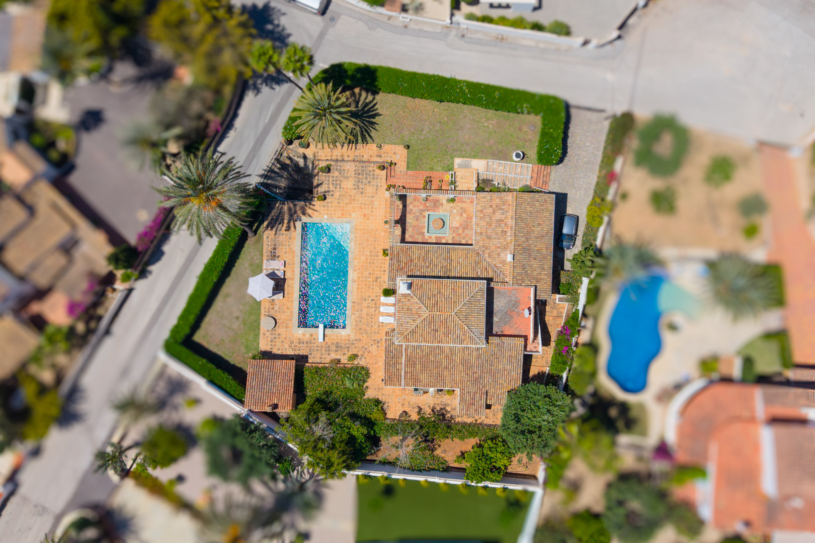 Vista aérea de la villa con piscina rectangular y techo de tejas rojas.