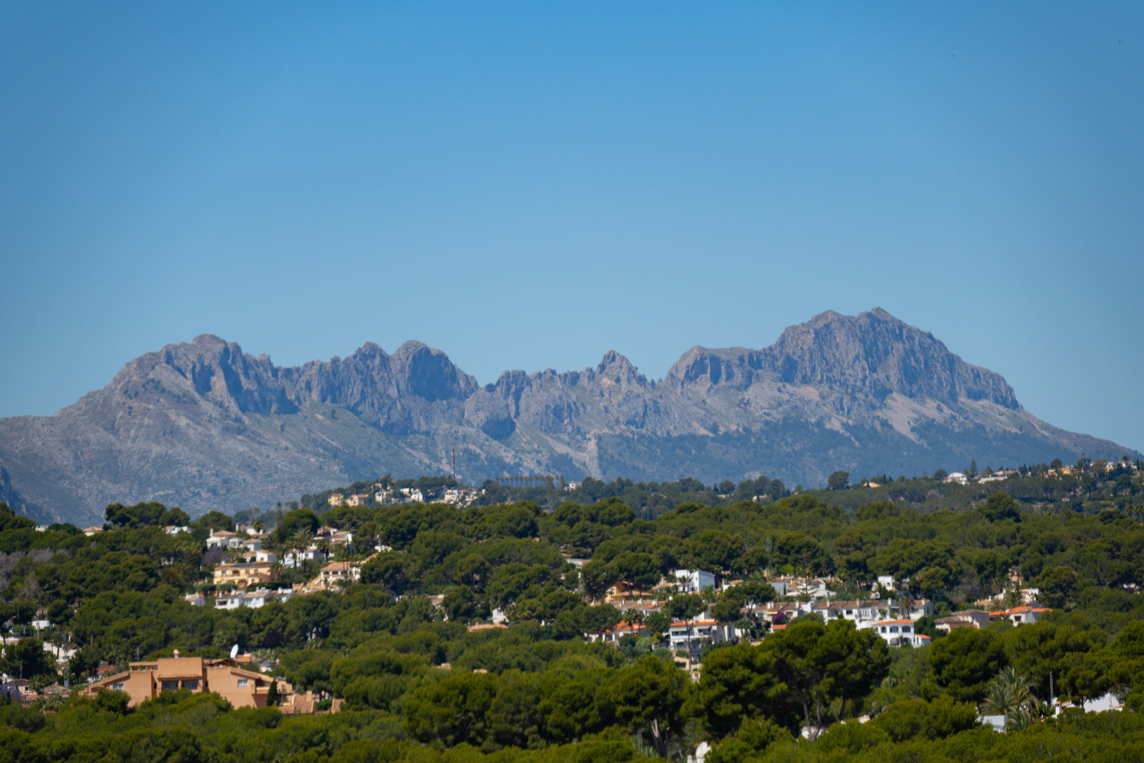 Vistas panorámicas de la Sierra de Bernia desde la villa, rodeada de vegetación y otras viviendas.