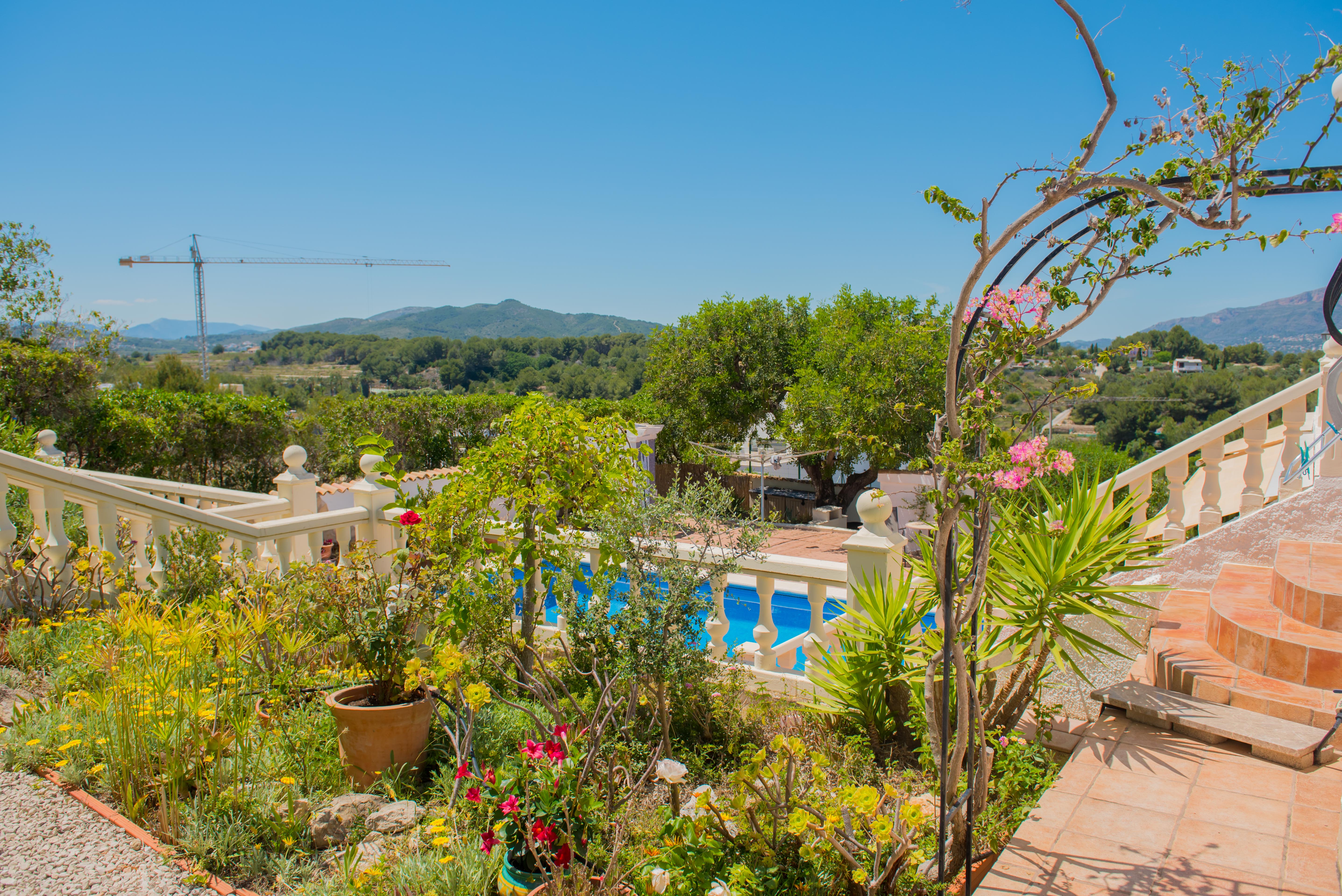 Jardín mediterráneo con piscina y barandilla de piedra caliza.