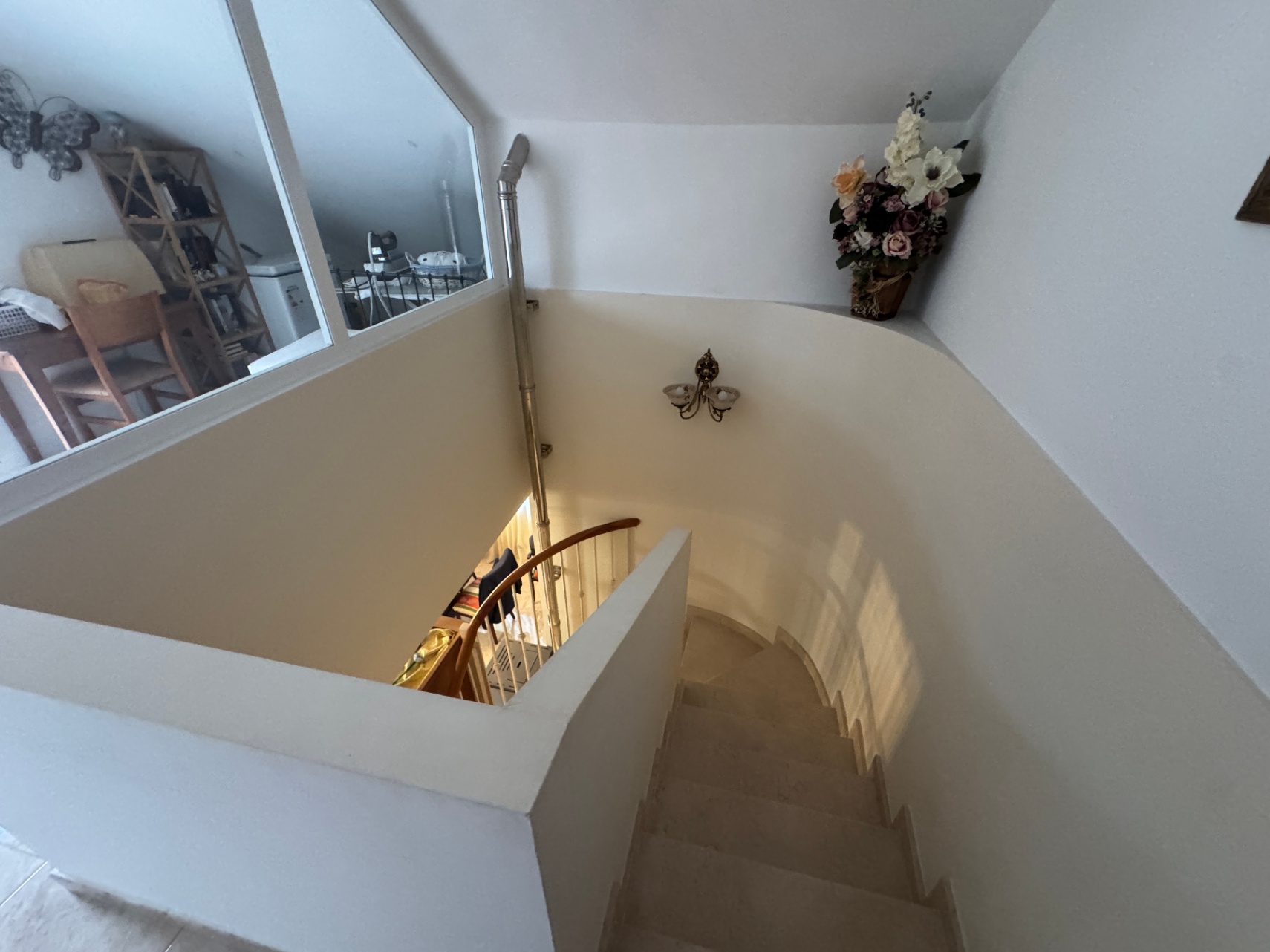 Detalle de la escalera interior con barandilla de madera y escalones de piedra.