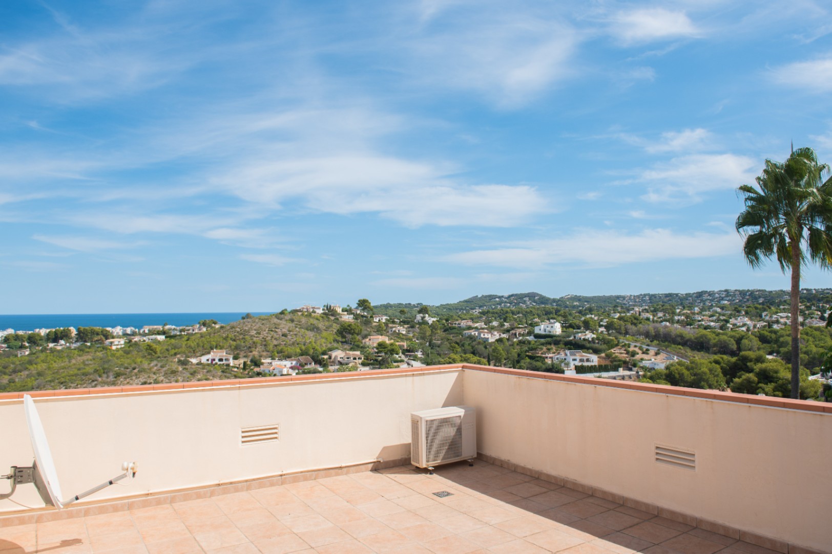 Terraza en la azotea con suelos cerámicos y vistas panorámicas al mar Mediterráneo, colinas arboladas y zonas residenciales bajo un cielo despejado.
