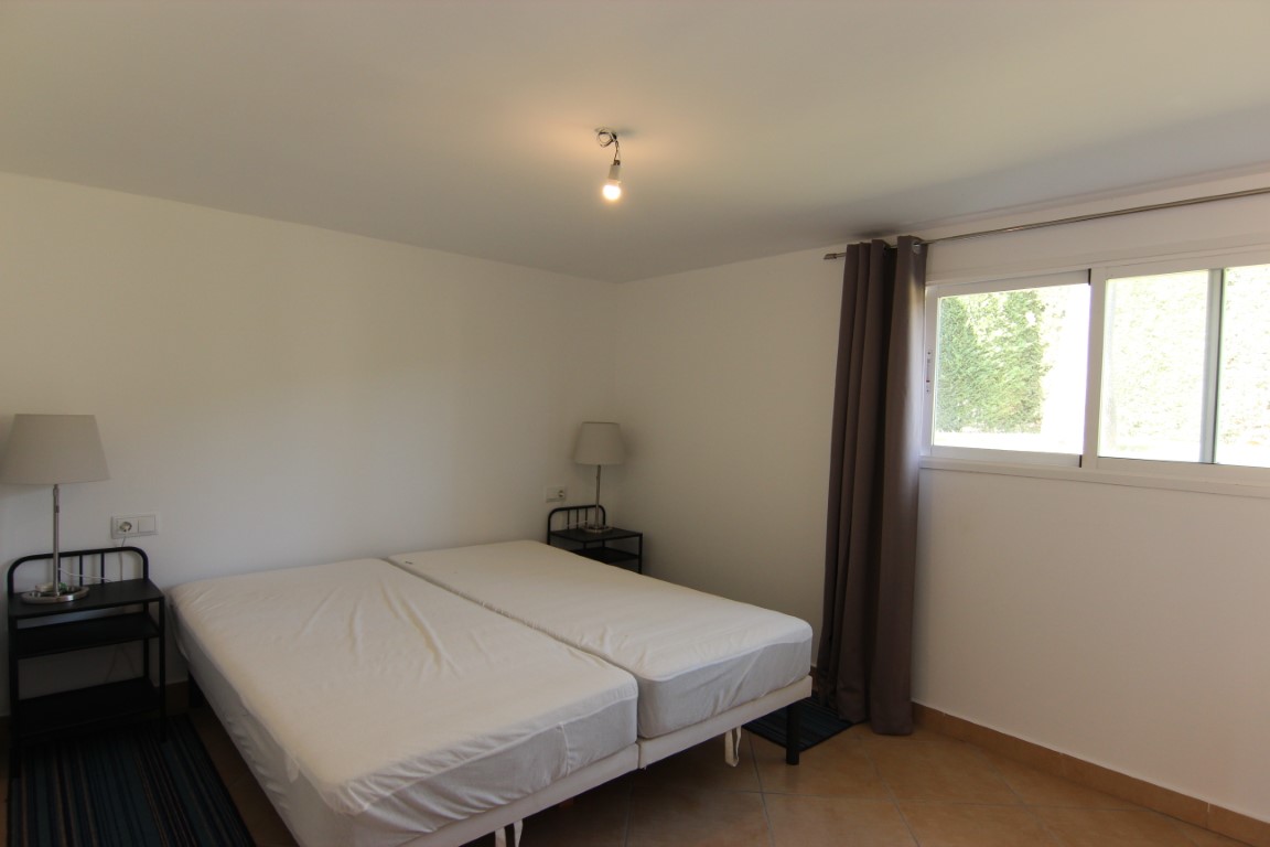 Dormitorio doble con suelos de gres, ventana corredera con vistas al jardín y mesitas de noche metálicas de estilo minimalista.