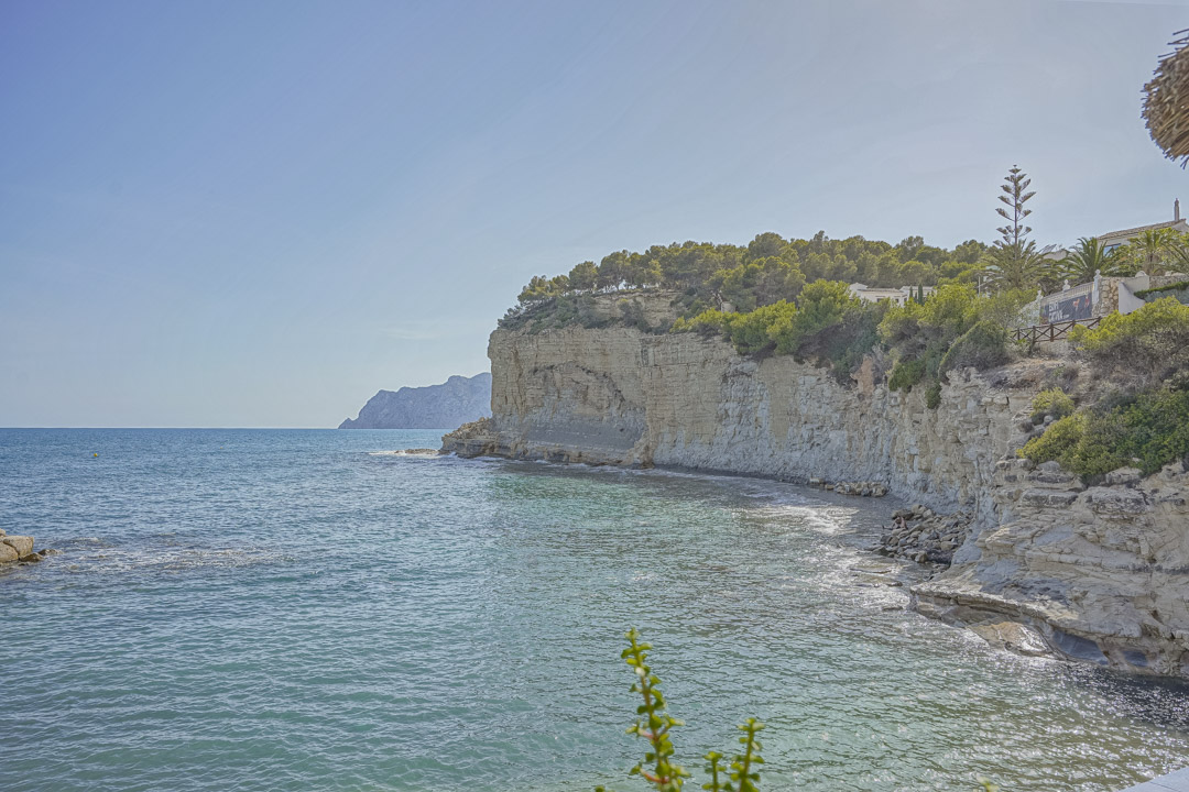 Vista panorámica de los acantilados de piedra caliza y aguas turquesas cerca de la playa de La Fustera, con vegetación mediterránea autóctona.