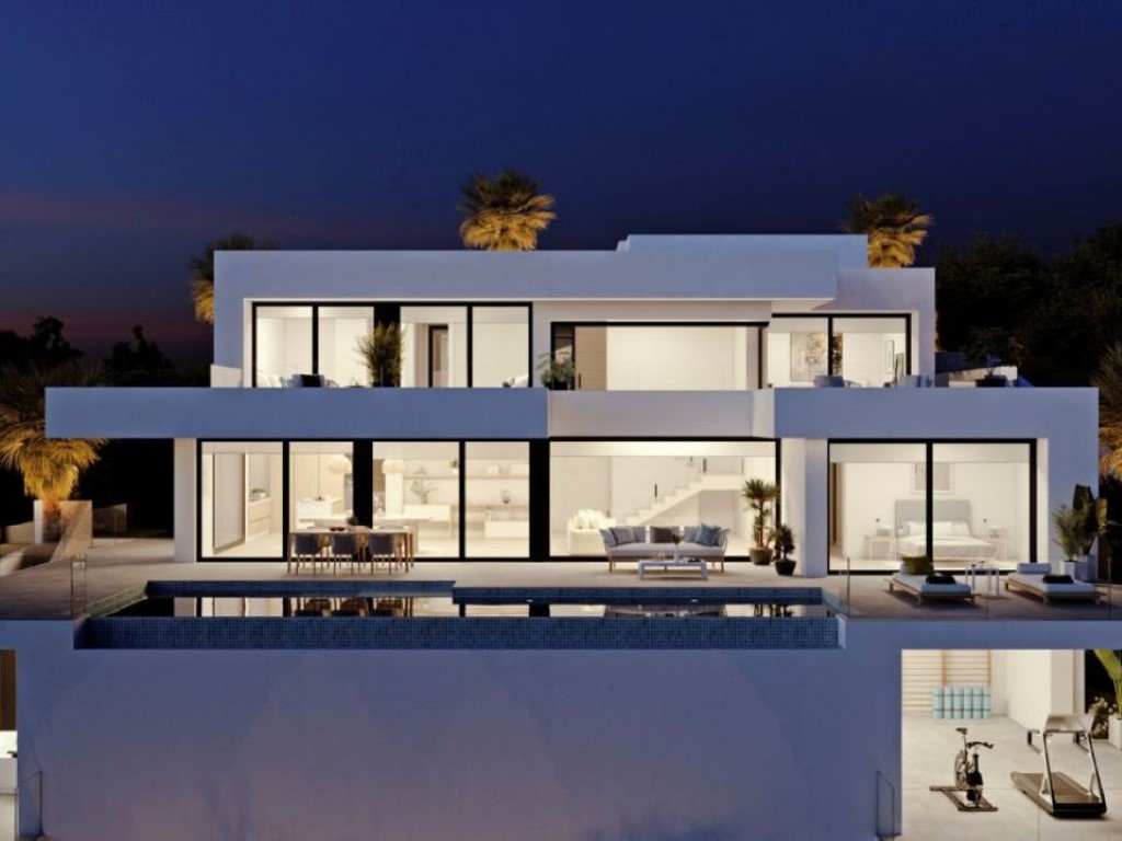Fachada nocturna de tres niveles con amplios ventanales, piscina infinita y gimnasio visible en la planta inferior bajo una arquitectura minimalista blanca.