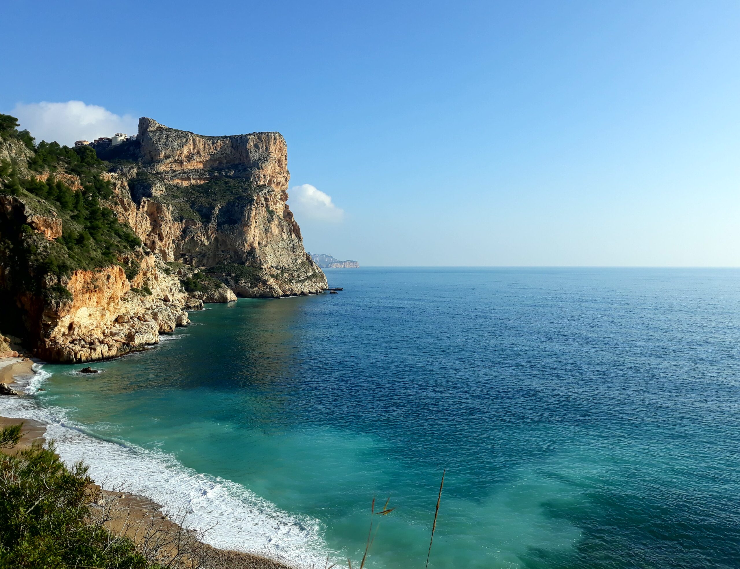 Vistas panorámicas de los acantilados de Cumbre del Sol y las aguas turquesas del Mediterráneo desde una posición elevada sobre la costa.
