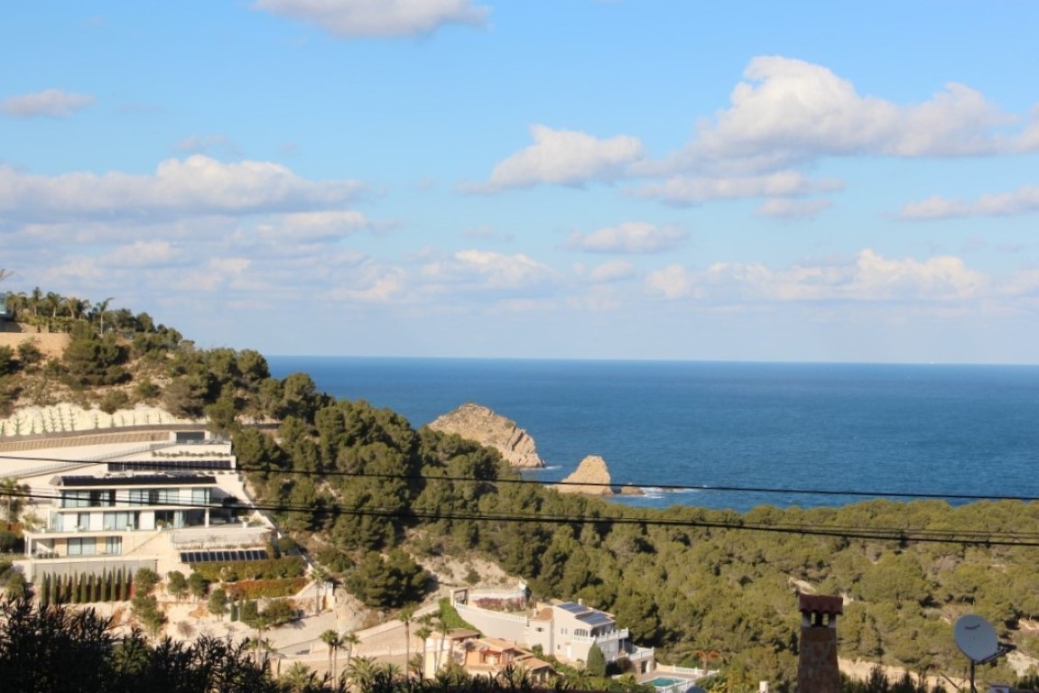 Vistas panorámicas al mar Mediterráneo y la costa de Jávea, destacando el entorno natural de pinos y la arquitectura moderna integrada en la ladera.