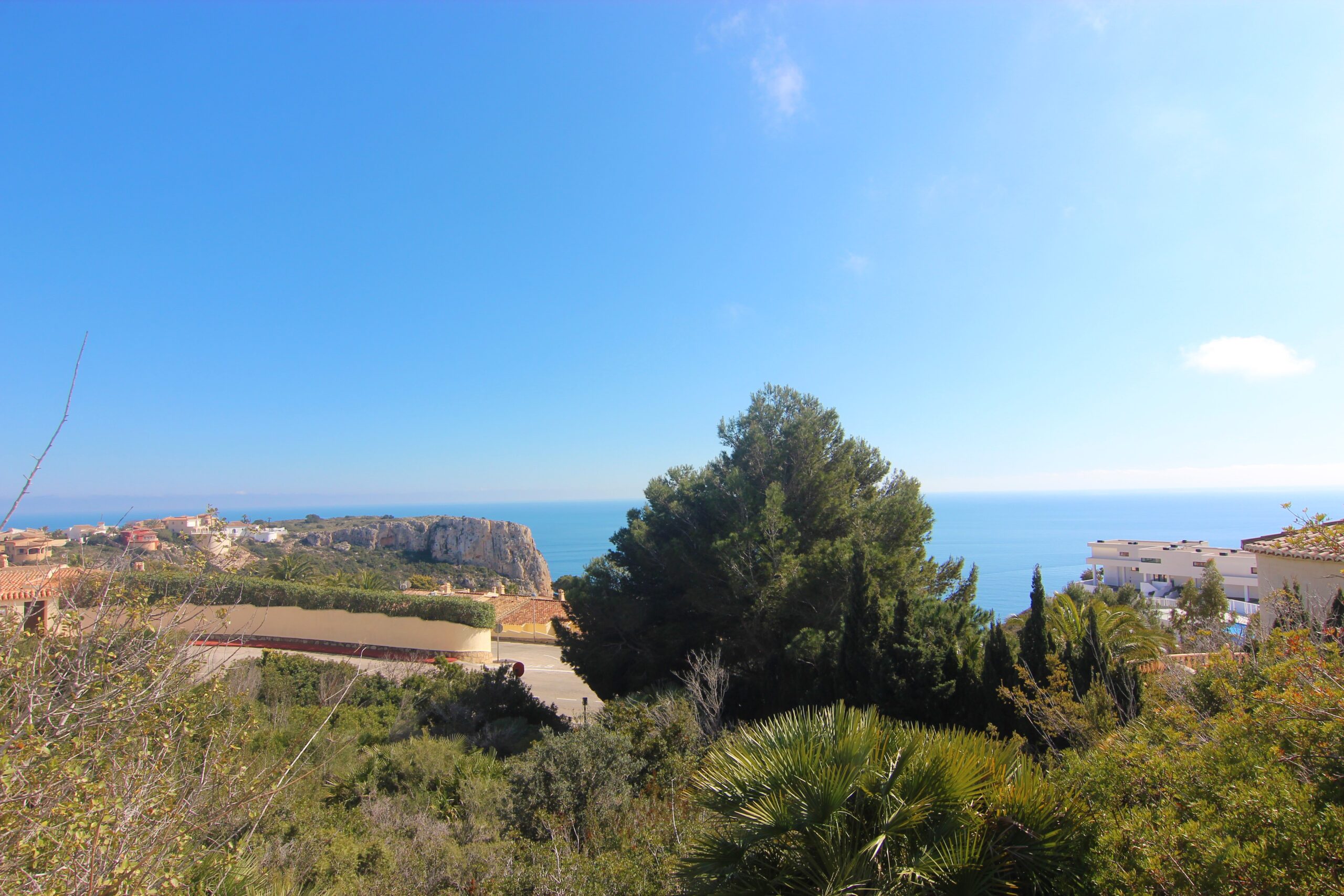 Vista panorámica del mar Mediterráneo y los acantilados de Cumbre del Sol desde una elevación rodeada de vegetación autóctona y pinos.