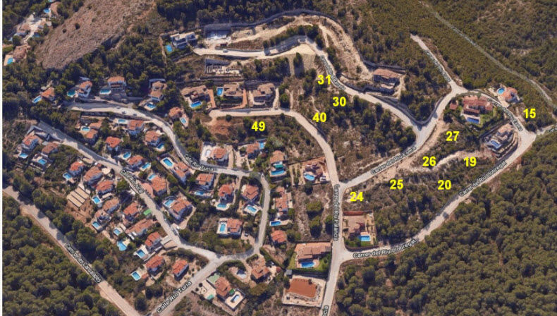 Vista aérea de la urbanización en Jávea, mostrando la disposición de las parcelas numeradas entre pinos, viales asfaltados y villas con piscina.