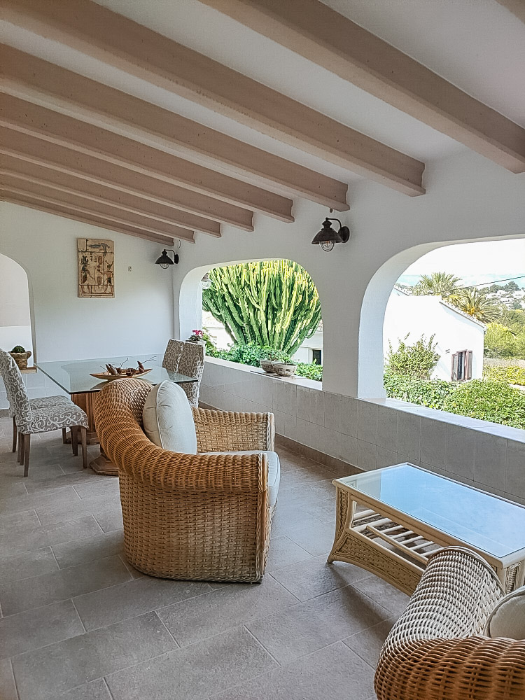 Amplia naya cubierta con techos de vigas de madera, mobiliario de mimbre y arcos tradicionales con vistas al jardín mediterráneo.