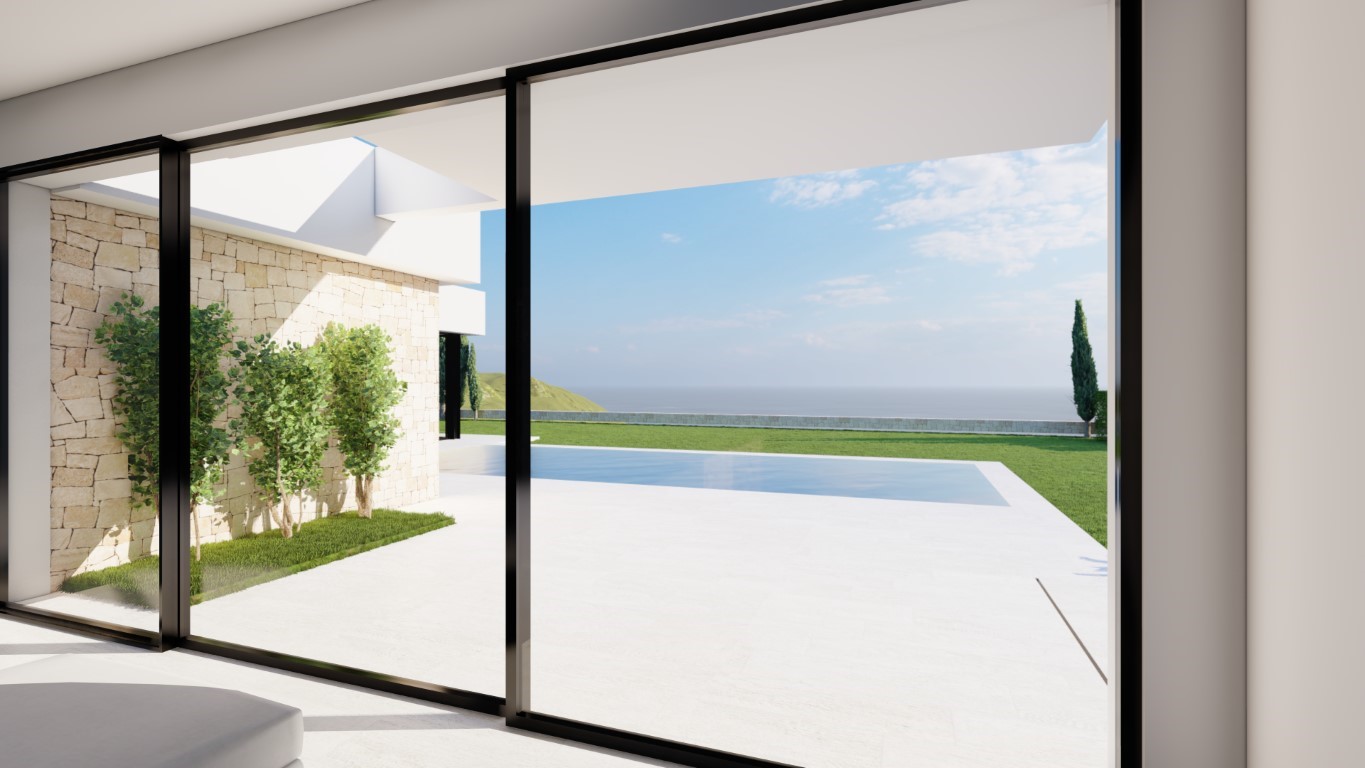Vista desde el interior a través de grandes ventanales hacia la terraza de piedra blanca, la piscina rectangular y el mar Mediterráneo al fondo.