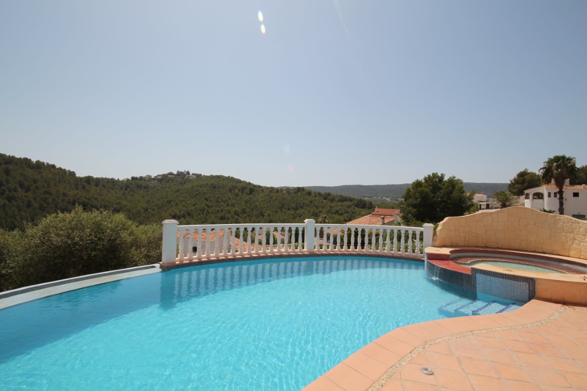 Terraza solárium con piscina infinita y jacuzzi integrado, delimitada por una balaustrada blanca con vistas despejadas a las colinas.