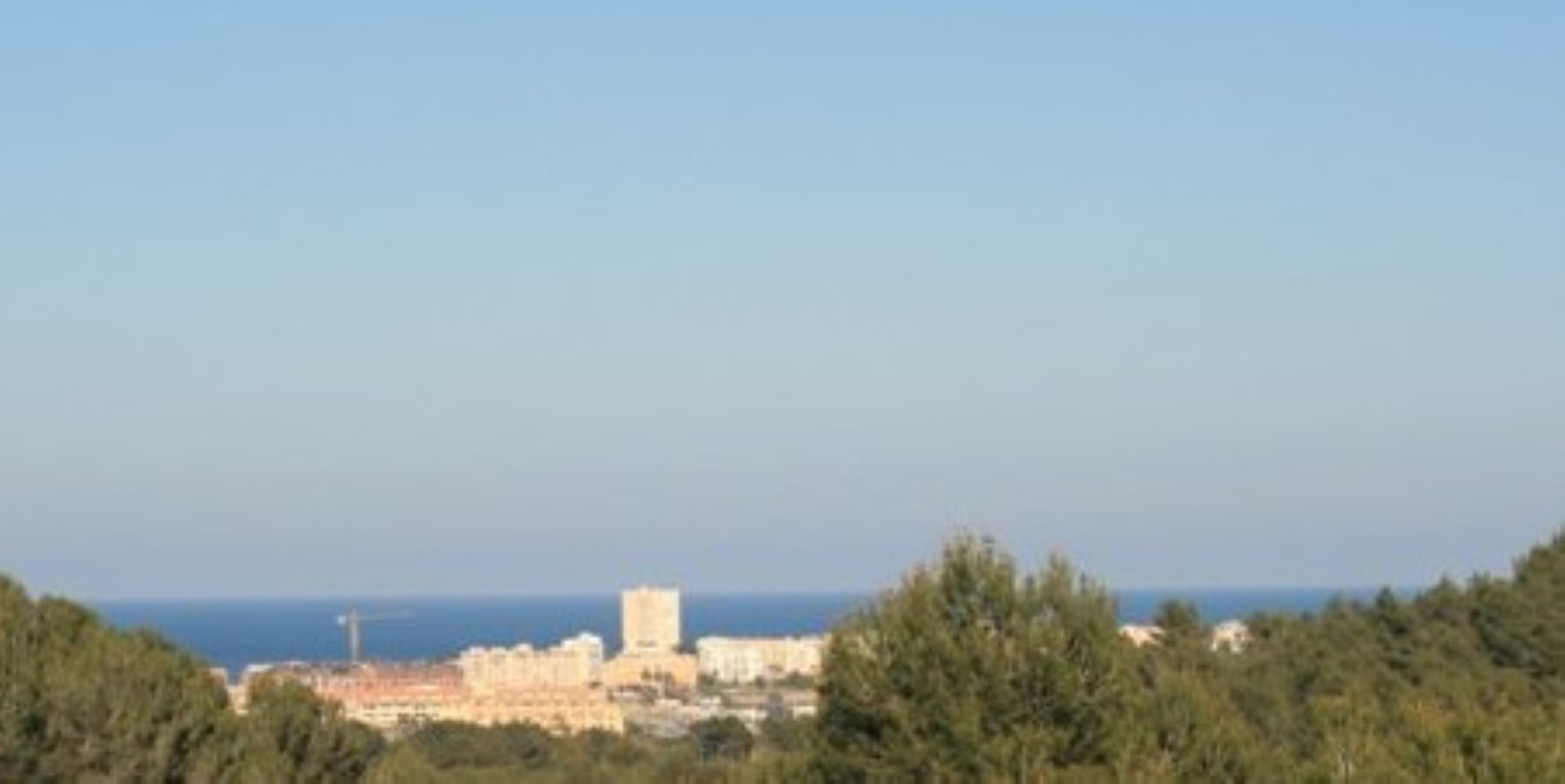Vistas panorámicas al mar Mediterráneo y al núcleo urbano costero desde la propiedad, enmarcadas por la vegetación autóctona de pinos.