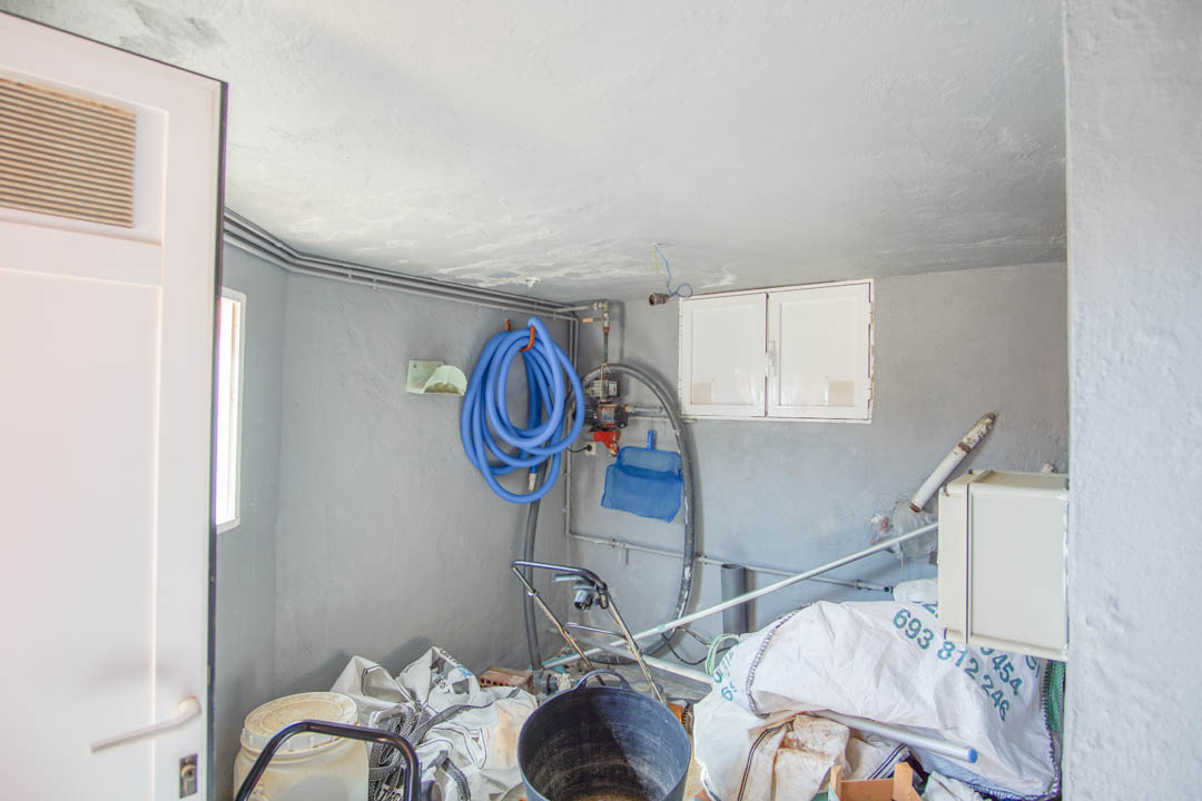 Cuarto técnico y de almacenamiento con paredes grises, equipado con manguera de piscina, red de limpieza y sistema de bombeo integrado.