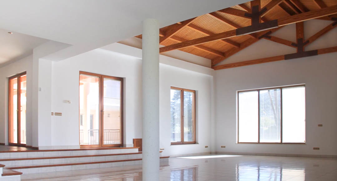 Amplio salón con techos altos de madera vista, suelos de gres pulido y grandes ventanales que aportan abundante luz natural a la estancia diáfana.
