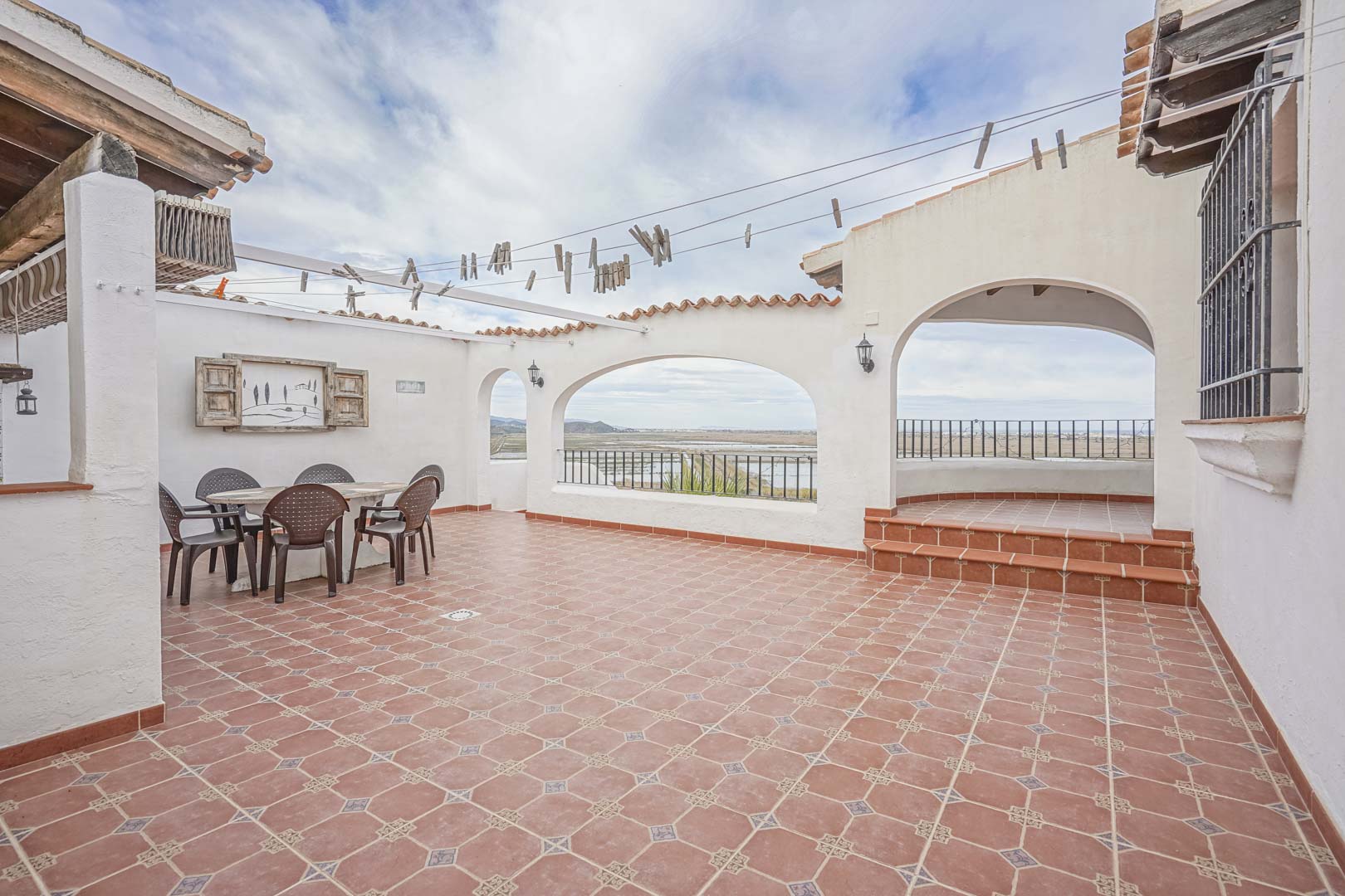 Amplia terraza con suelo de baldosas y vistas a la reserva natural, ideal para comidas al aire libre.