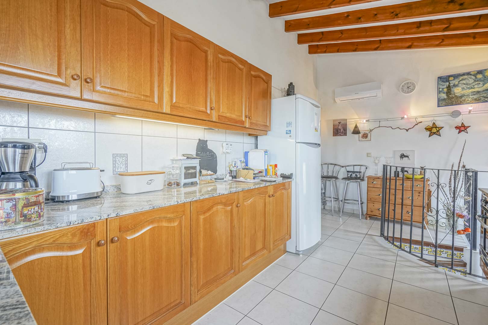 Cocina americana renovada con armarios de madera, encimera de granito y electrodomésticos modernos.