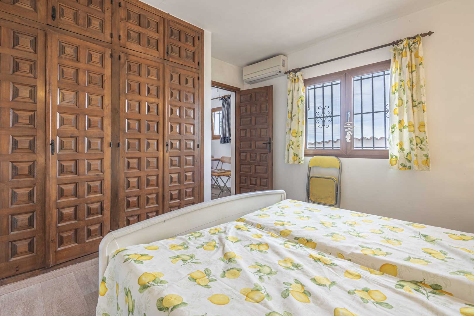 Dormitorio con armario de madera tallada y ropa de cama con estampado de limones.