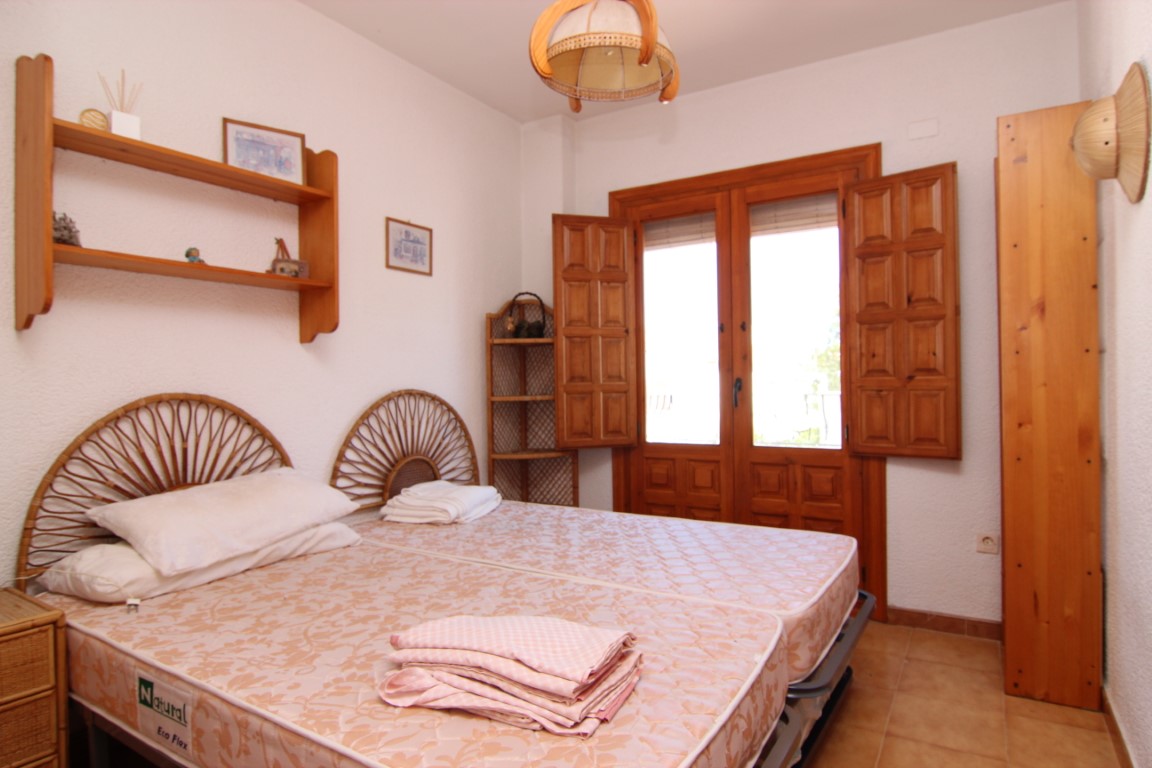 Dormitorio con camas individuales, cabeceros de ratán y carpintería de madera.