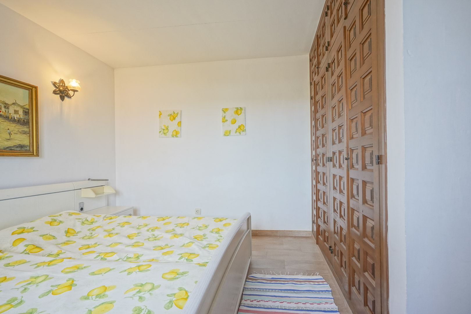 Dormitorio luminoso con cama, armario de madera y decoración temática de limones.