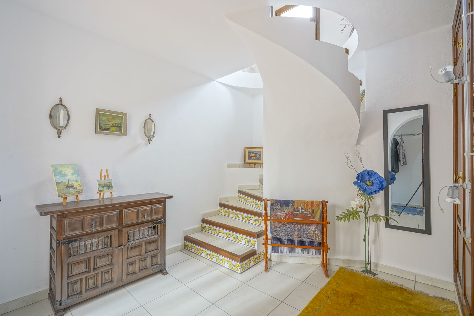 Entrada luminosa con escalera de caracol y detalles rústicos, como el aparador de madera.