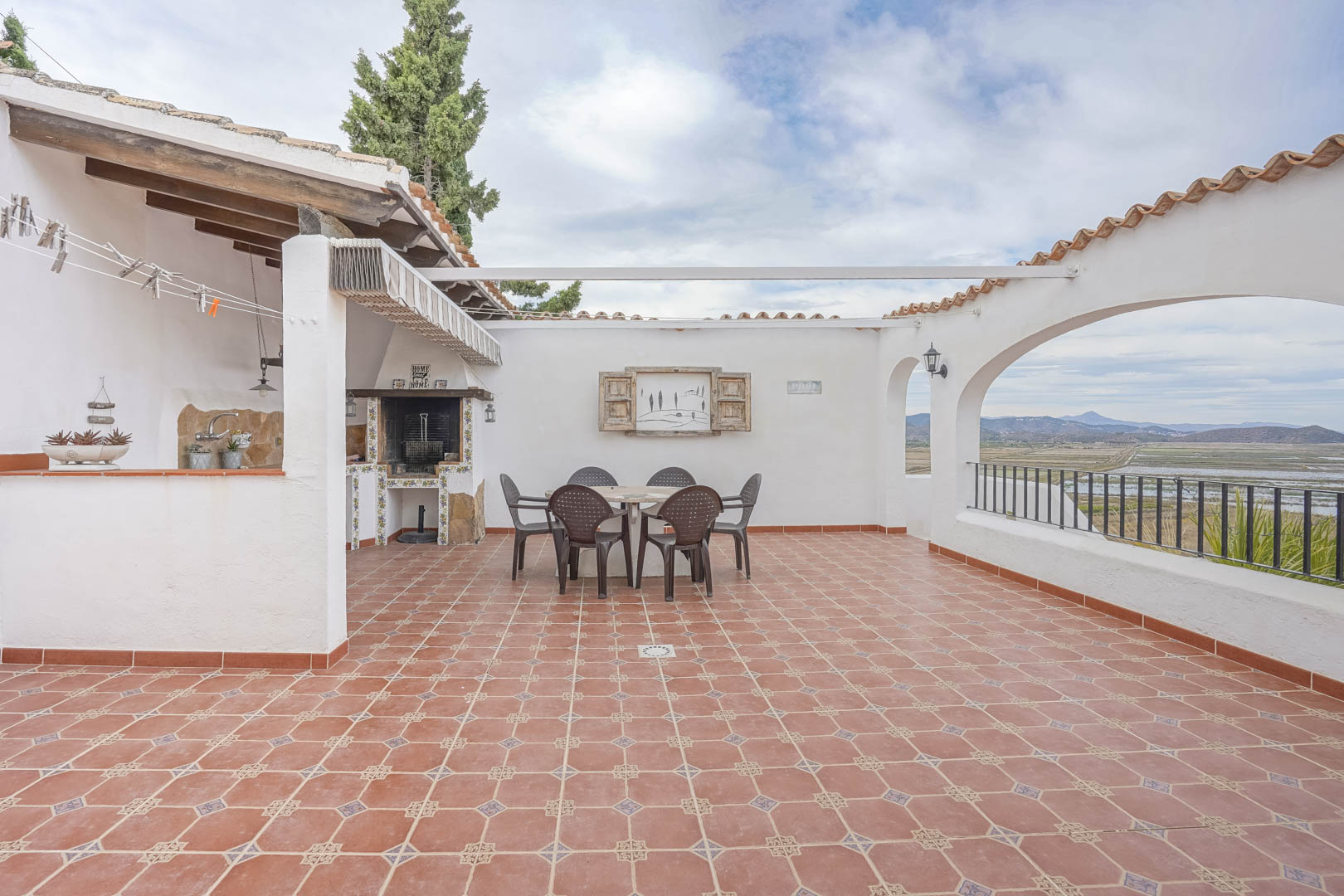 Terraza con barbacoa y vistas panorámicas en villa de Monte Pego. Suelos de baldosas y mobiliario exterior.