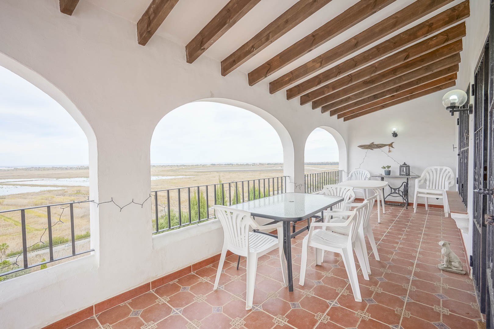 Terraza cubierta con vistas panorámicas, techo con vigas de madera y suelo de baldosas de terracota.