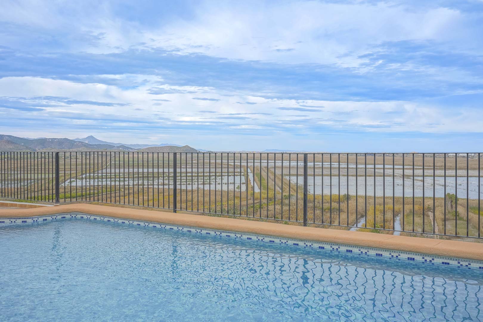 Vista de la piscina con barandilla y el paisaje de Marjal de Pego.