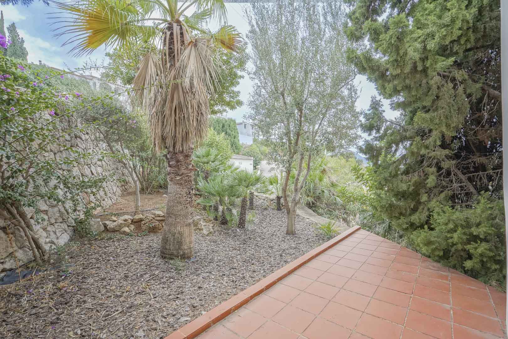 Vista del jardín de fácil mantenimiento con riego automático, desde la terraza cubierta con baldosas de terracota.