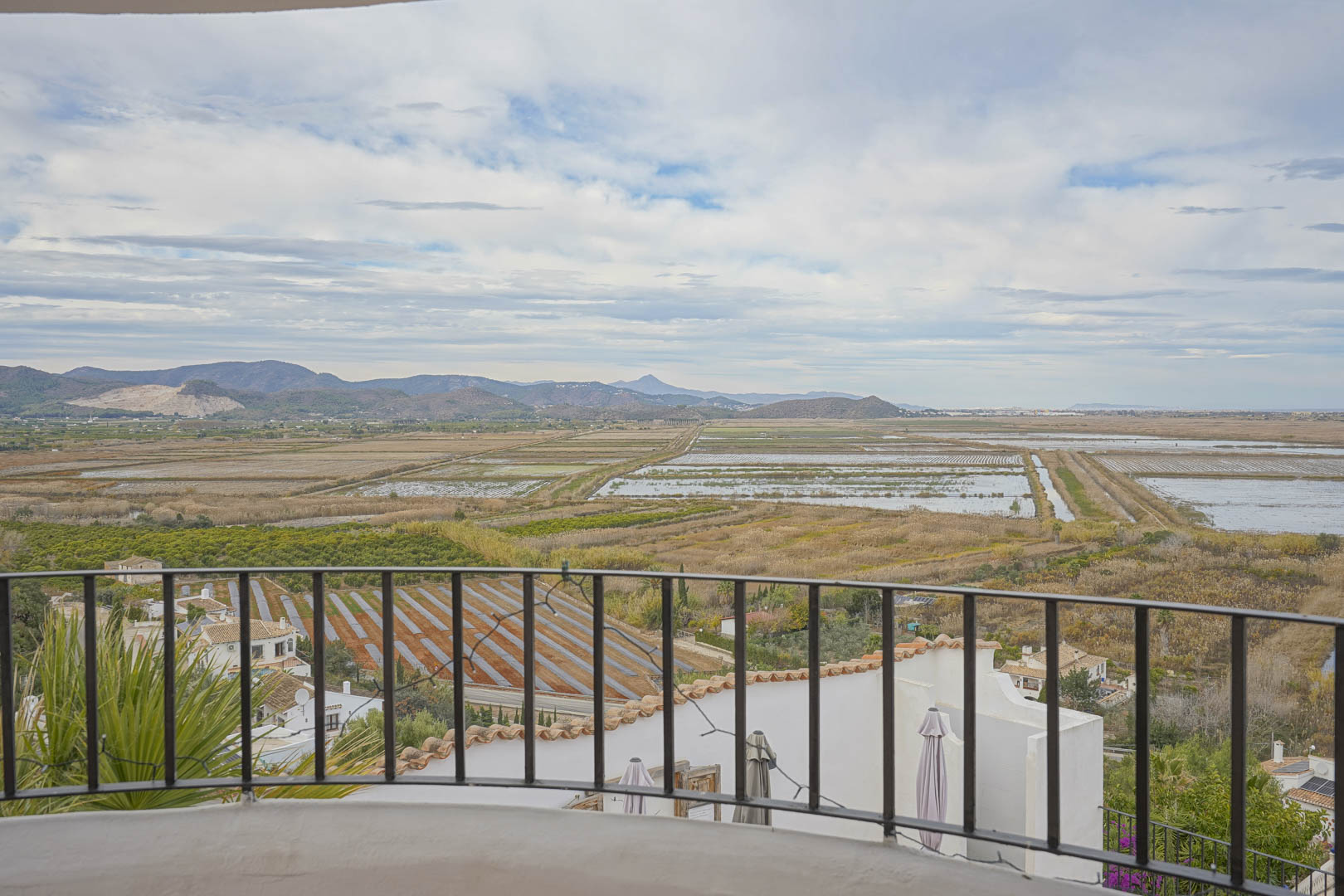 Vistas panorámicas desde la terraza con barandilla de hierro forjado sobre el paisaje de arrozales y montañas.