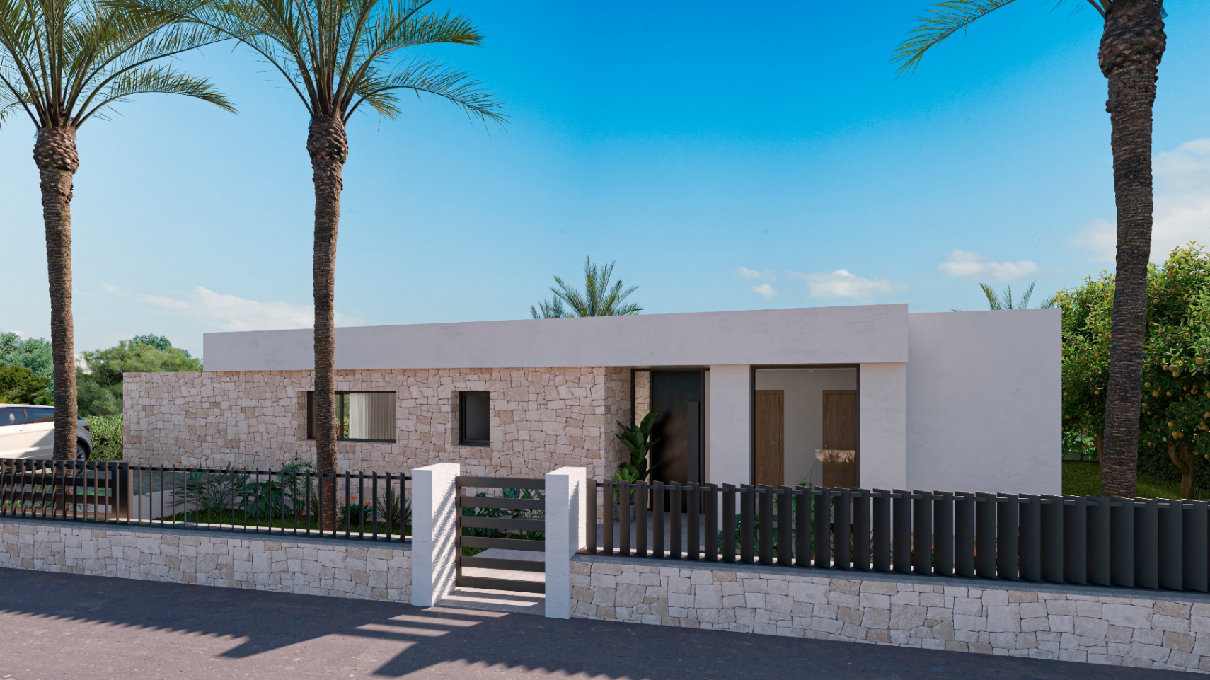 Fachada de la villa con muros de piedra y valla metálica negra.