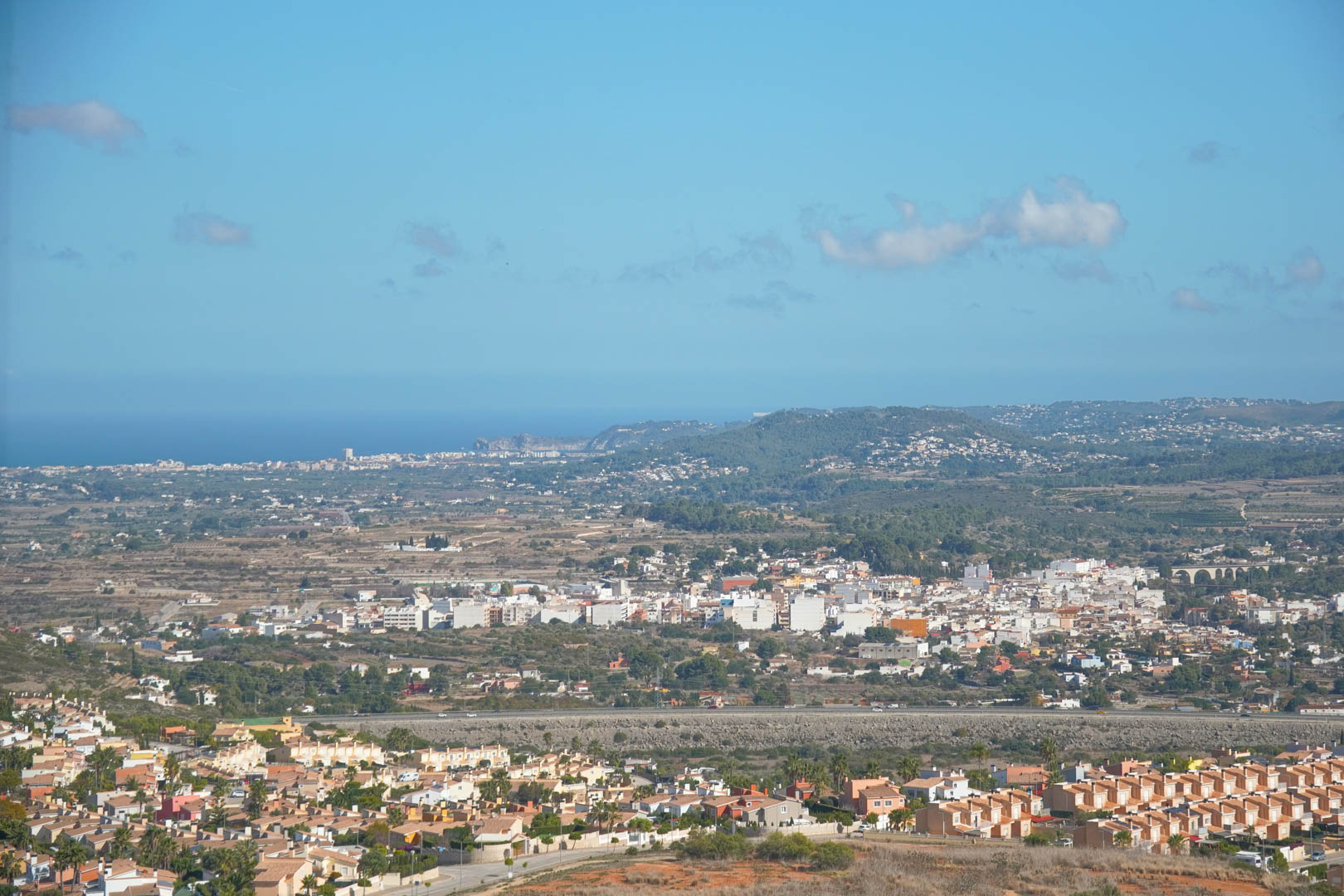 Vista panorámica desde la propiedad hacia el valle de Pedreguer, con el mar Mediterráneo en el horizonte bajo un cielo despejado.
