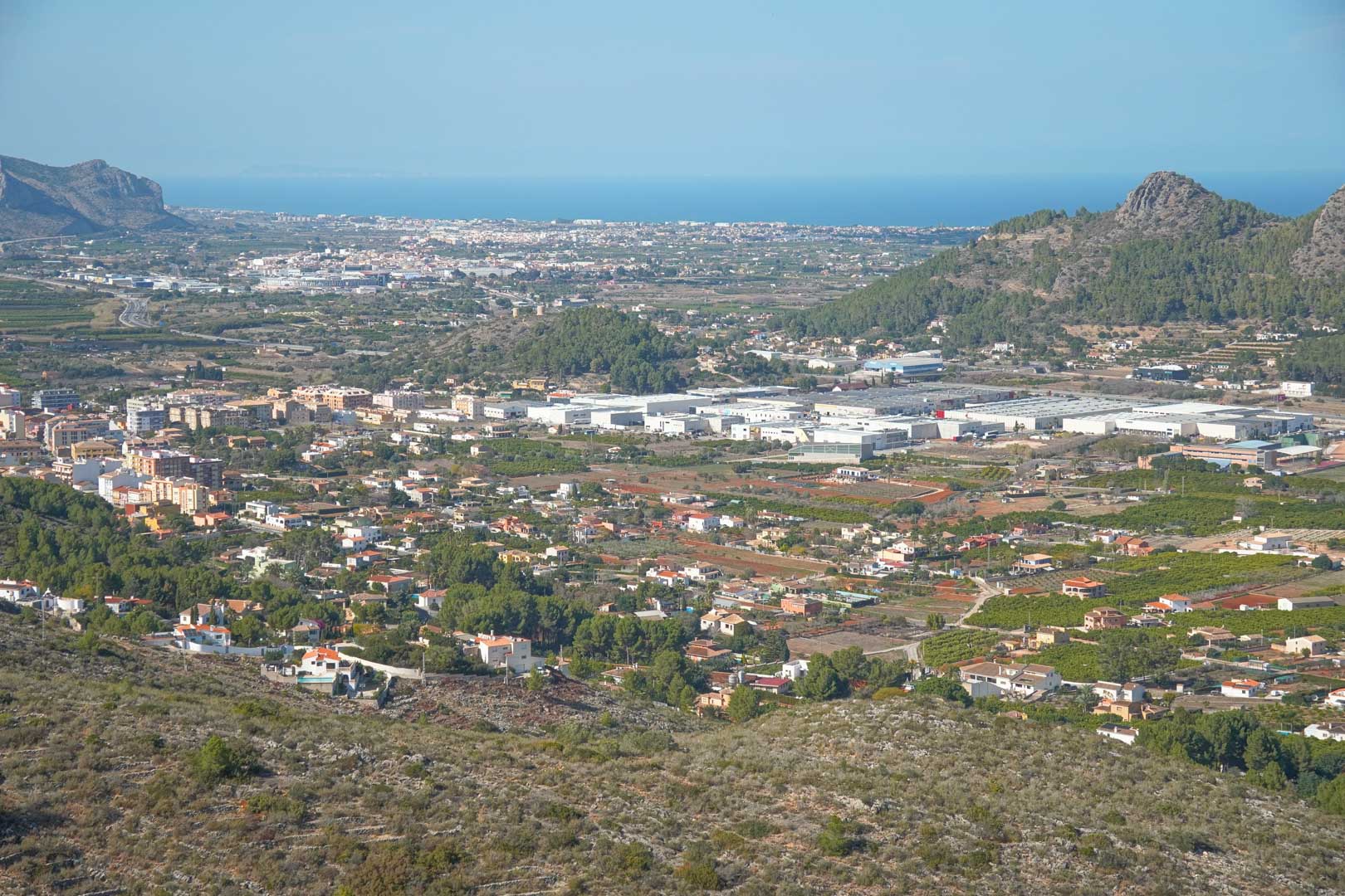 Vistas panorámicas desde la propiedad hacia el valle de Pedreguer, mostrando el entorno urbano y la silueta del mar Mediterráneo en el horizonte bajo un cielo despejado.