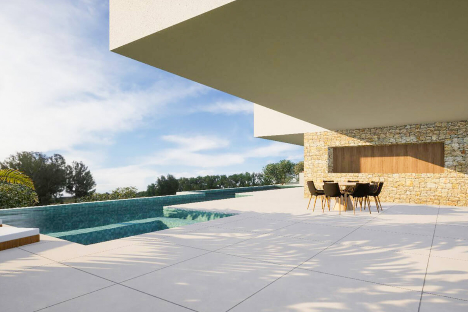 Terraza exterior con suelo de gran formato, zona de comedor bajo voladizo y piscina desbordante con mosaico turquesa frente a un muro de piedra natural.