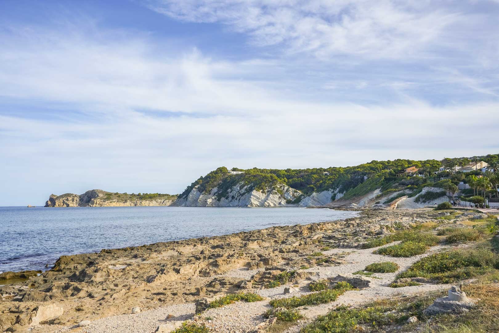 Vista panorámica de la costa rocosa de Jávea, mostrando acantilados de piedra caliza y la orilla mediterránea bajo un cielo despejado.