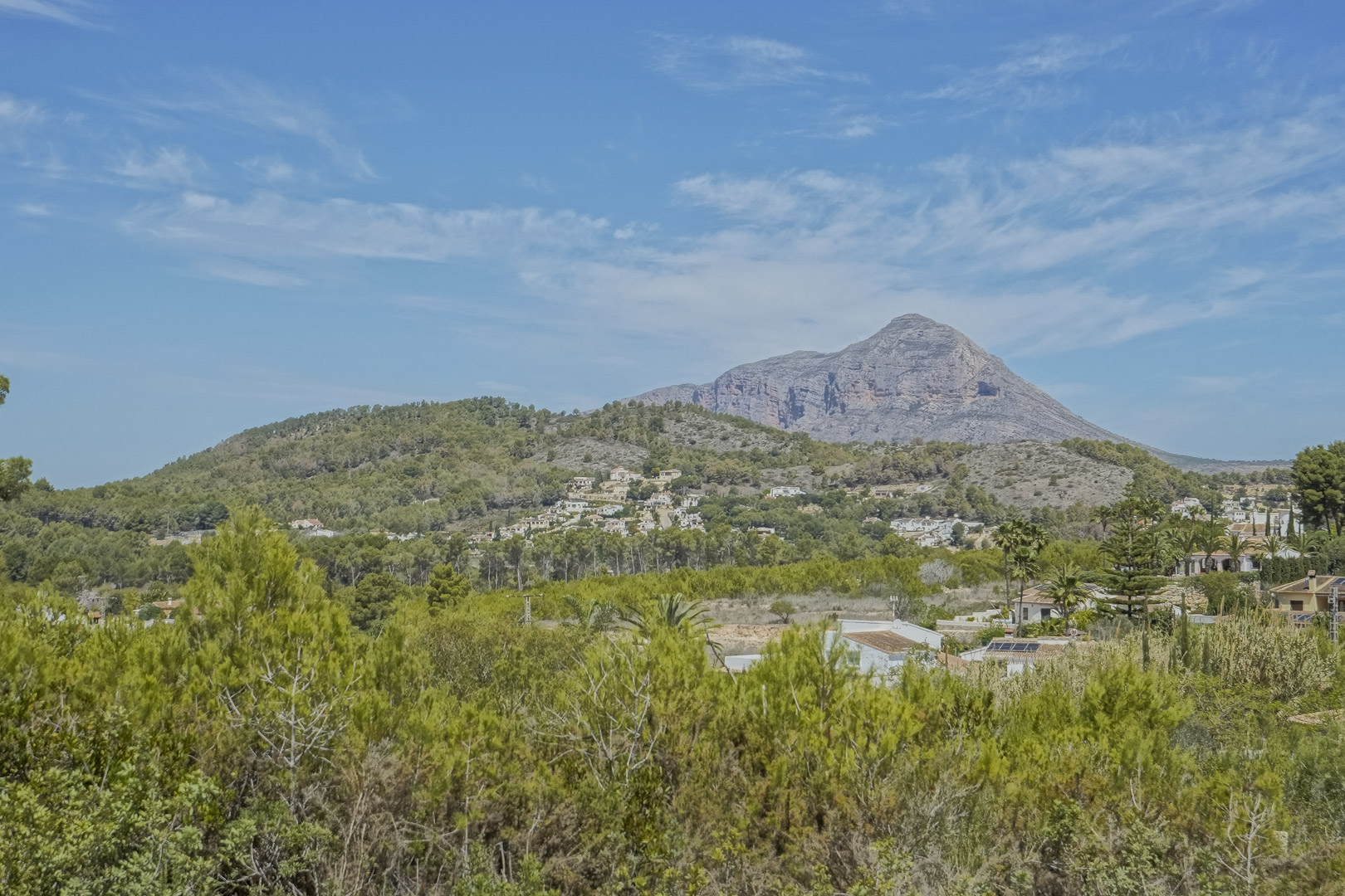Vistas panorámicas despejadas al macizo del Montgó y al entorno natural de Jávea, rodeado de vegetación mediterránea y colinas onduladas bajo un cielo despejado.