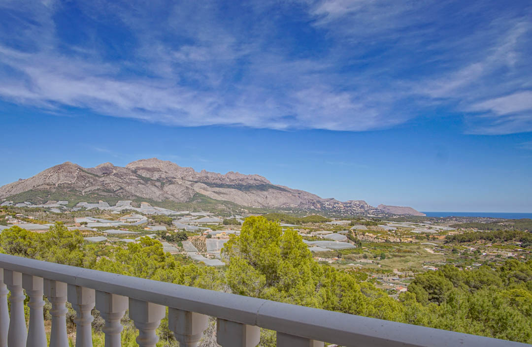 Vistas panorámicas desde la terraza con balaustrada blanca, mostrando el valle de La Nucía, las montañas y el mar Mediterráneo en el horizonte.