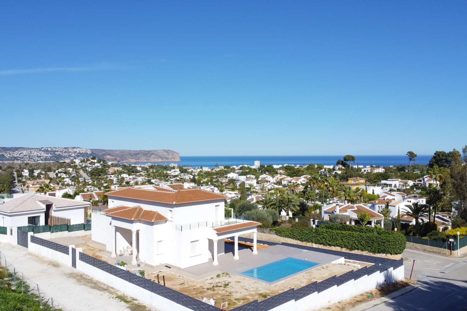 Vista aérea de la villa en Pinosol con tejado de teja cerámica, piscina rectangular y vistas panorámicas al mar Mediterráneo y al cabo de Jávea.