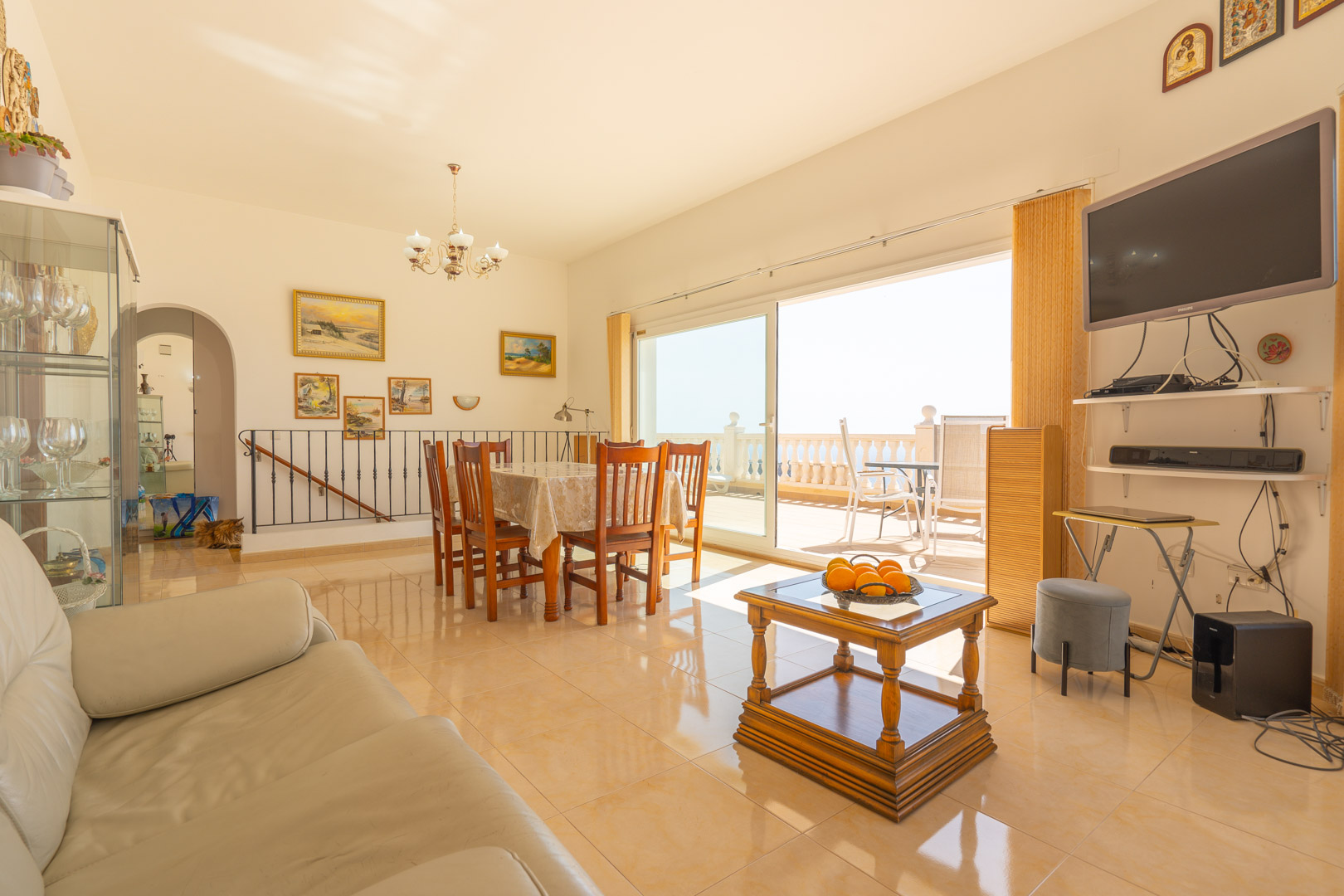 Salón-comedor luminoso con suelos de gres, mobiliario de madera y amplios ventanales correderos que conectan directamente con la terraza exterior.