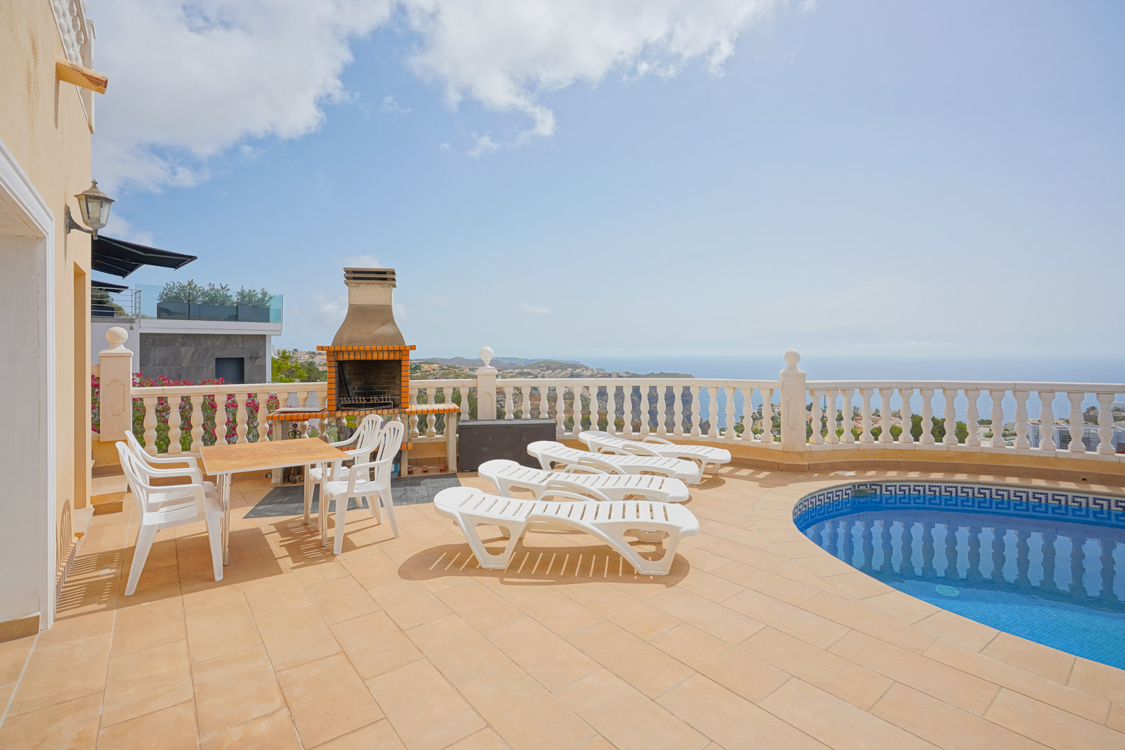 Terraza exterior con piscina, zona de barbacoa de obra y mobiliario. Ofrece vistas panorámicas al mar Mediterráneo y los acantilados de Cumbre del Sol.