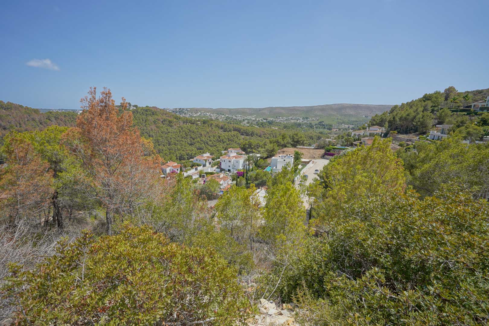 Vista panorámica desde la elevación del terreno hacia el valle, mostrando la vegetación autóctona y las villas blancas integradas en el paisaje montañoso.