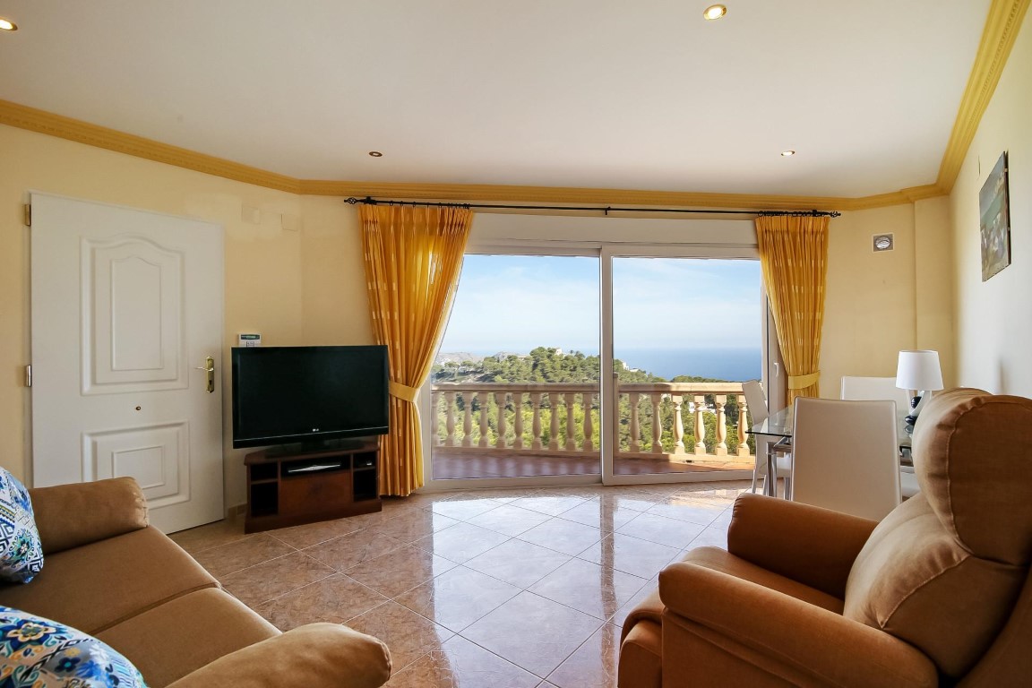 Salón luminoso con suelos cerámicos, molduras decorativas y amplios ventanales que ofrecen vistas panorámicas al mar Mediterráneo y al entorno natural de Benimeit.