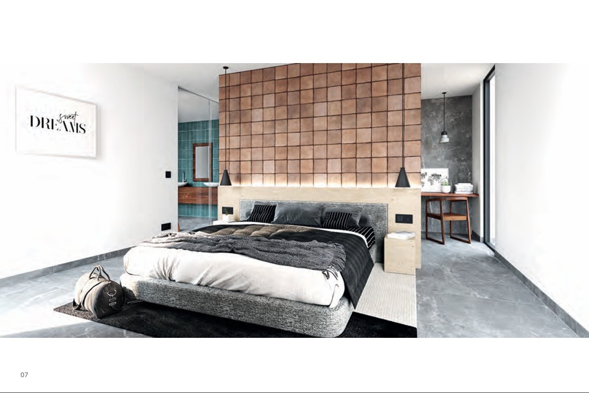 Dormitorio principal con pared de azulejos terracota, cabecero de madera con iluminación LED integrada y baño en suite visible tras un panel de cristal.