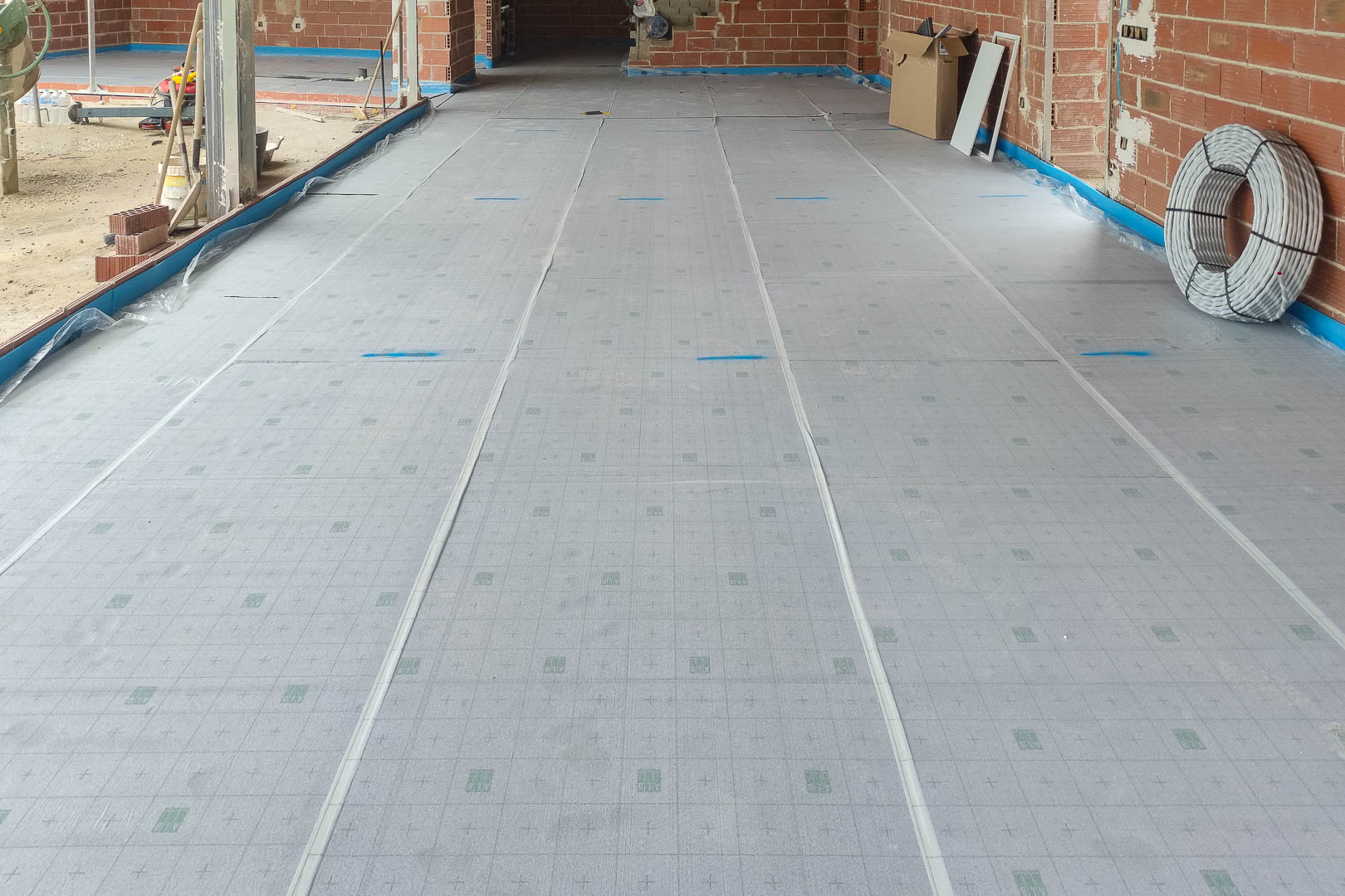 Proceso de instalación del aislamiento térmico para el sistema de calefacción por suelo radiante, mostrando la base técnica sobre la estructura de obra.