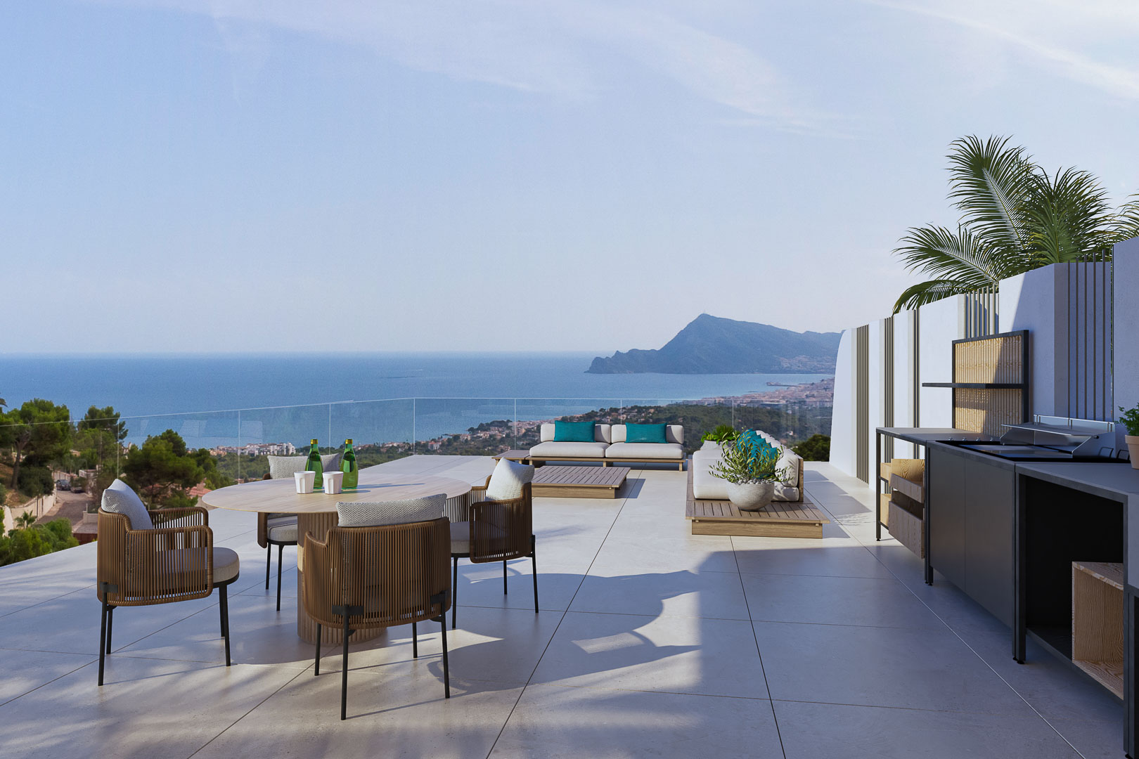Terraza panorámica con cocina exterior, comedor y zona lounge. Vistas al mar y la montaña, barandillas de cristal y suelo de gres porcelánico de gran formato.