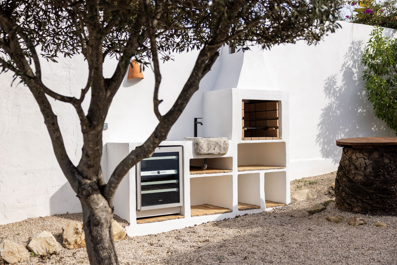 Detalle de la cocina exterior con barbacoa de obra, fregadero de piedra y botellero en Tosalet, Jávea.