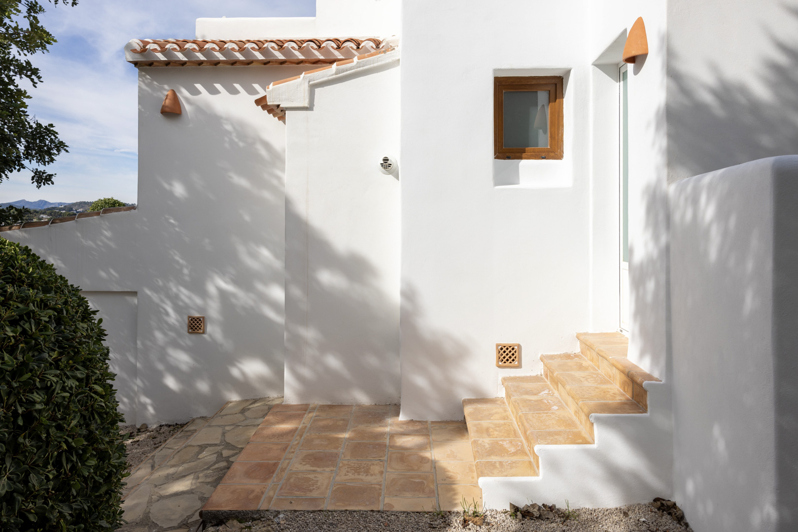 Exterior de villa en Jávea con paredes blancas, tejas de terracota y escaleras de acceso.