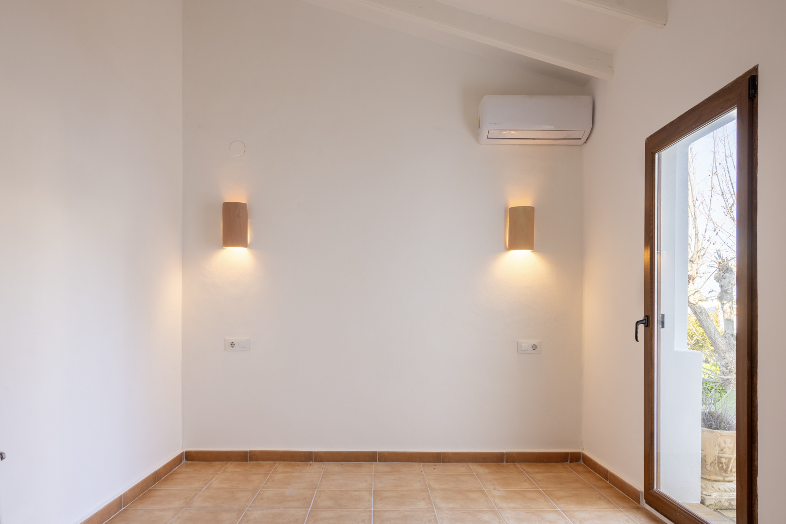 Habitación luminosa con apliques de madera y suelo de baldosas, con acceso al exterior.