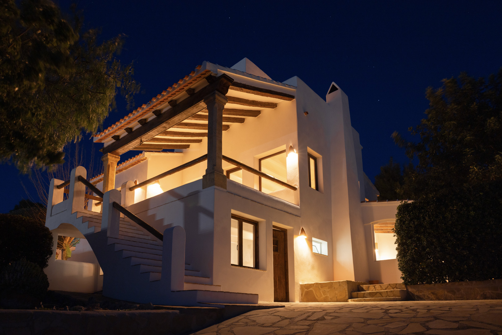 Vista nocturna de villa en Tosalet, Jávea. Arquitectura mediterránea con terraza cubierta, iluminación cálida y detalles de piedra.