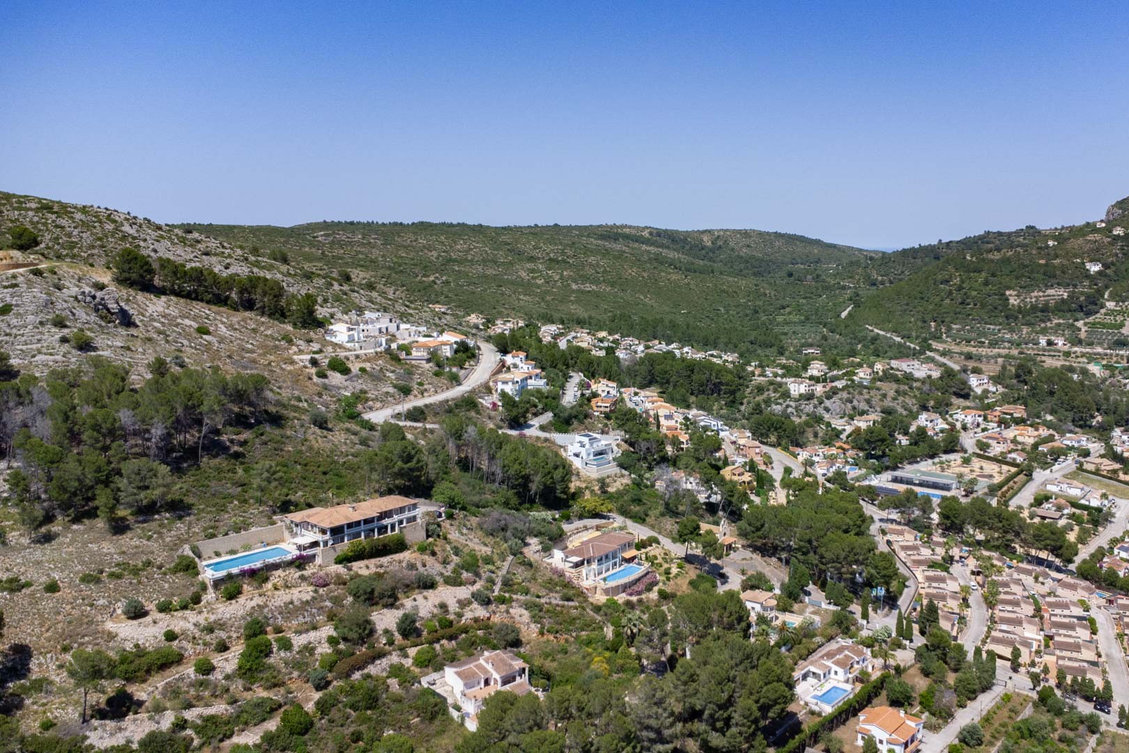 Vista aérea de la urbanización en Alcalalí, destacando la ubicación elevada de las parcelas y la integración de las viviendas en el entorno natural del valle.